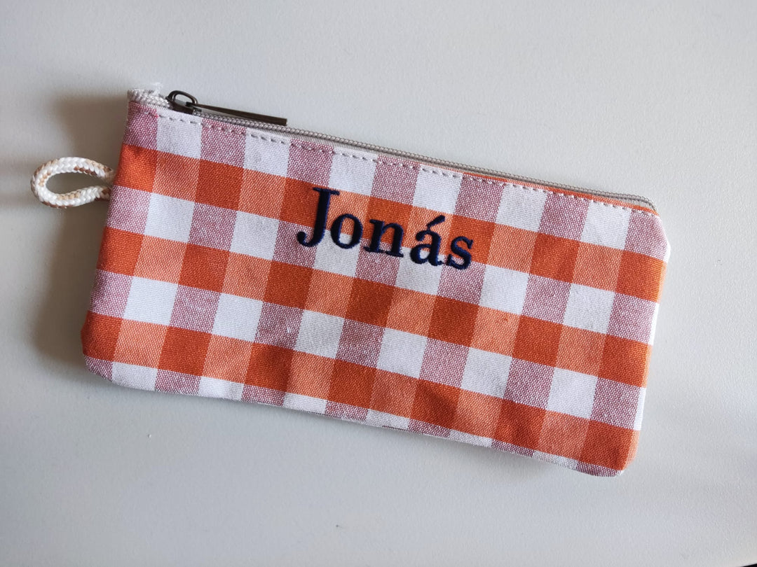 Primer plano del estuche Vichy negro con el nombre  bordado en rosa

