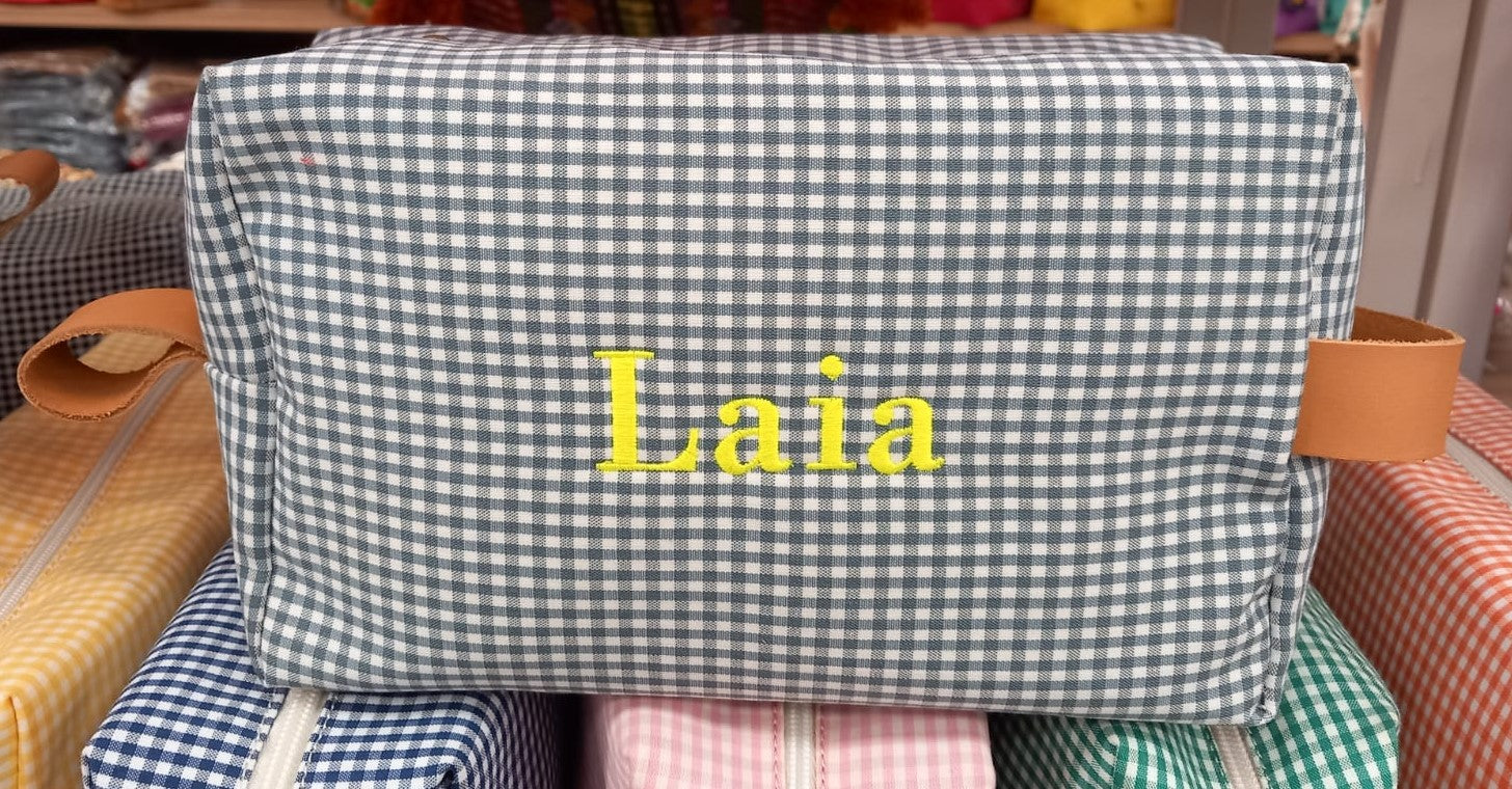 Neceser de cuadros Vichy gris personalizado con el nombre "Laia" bordado en amarillo y asa de piel