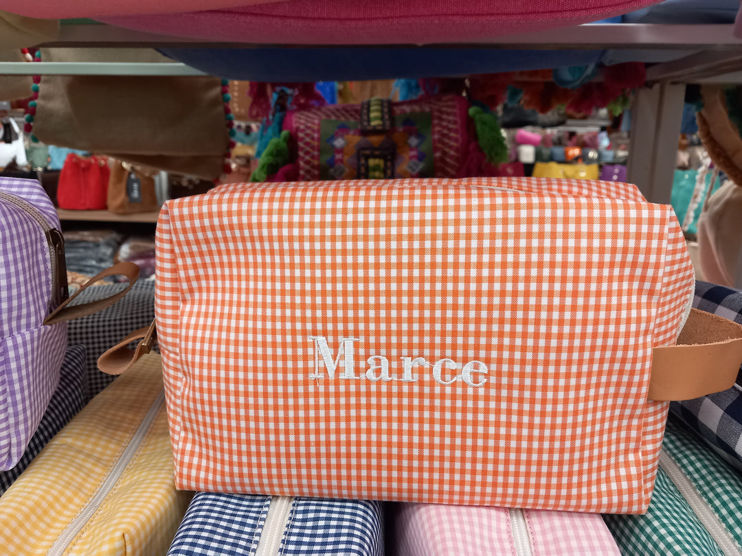 Neceser color naranja con cuadros blancos y el nombre "Marce" bordado, práctico y bonito