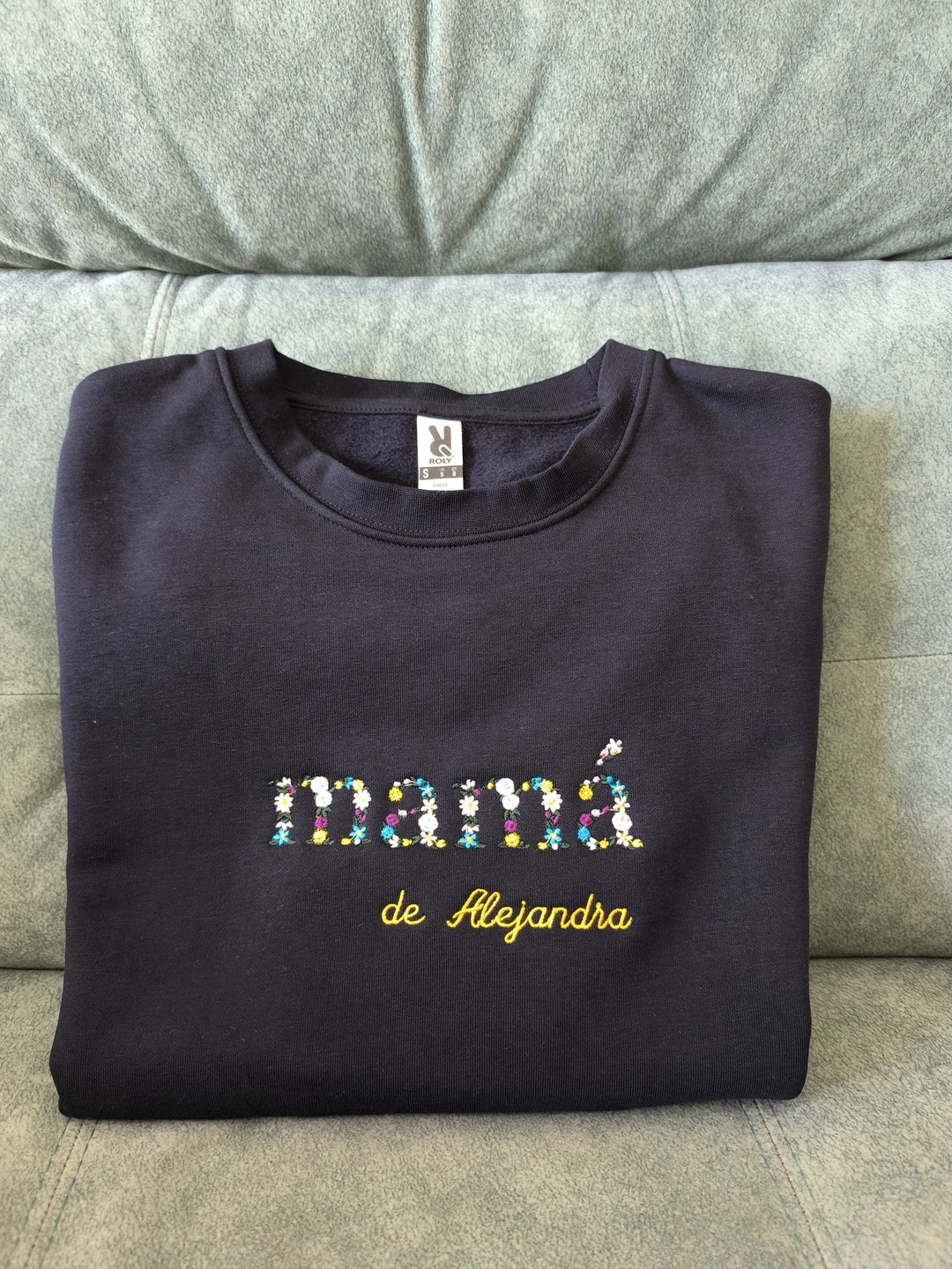 Detalle de varias sudaderas personalizadas con iniciales y nombres bordados en hilo colorido