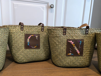 Bolso de rafia con panel de piel e inicial personalizada.

